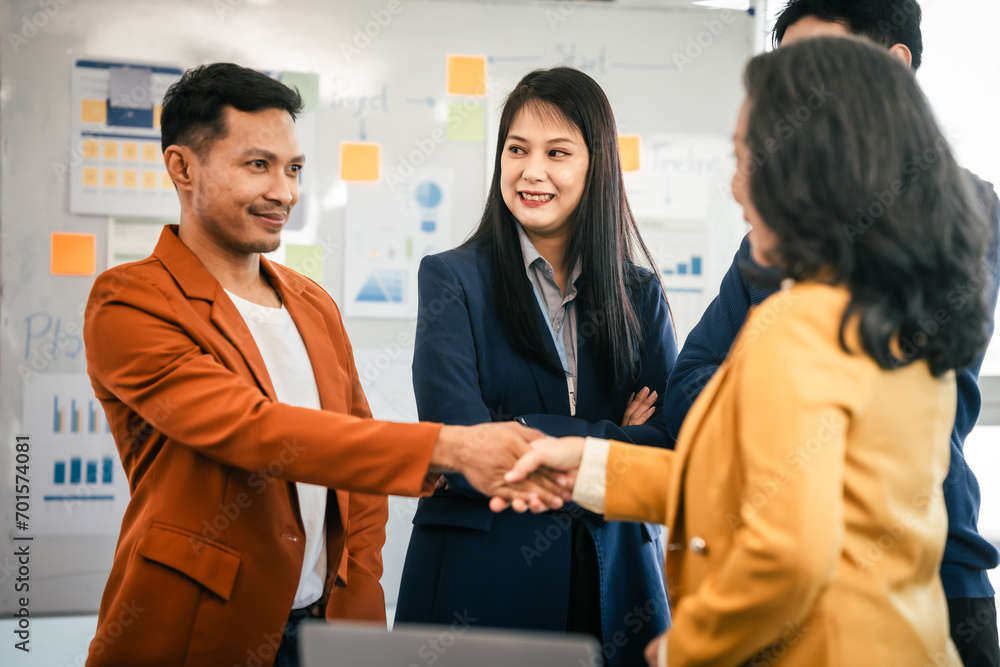 Fototapeta premium Asian business professionals team actively engaged in collaborative meeting in boardroom, sharing opinions and working together with visible happiness.