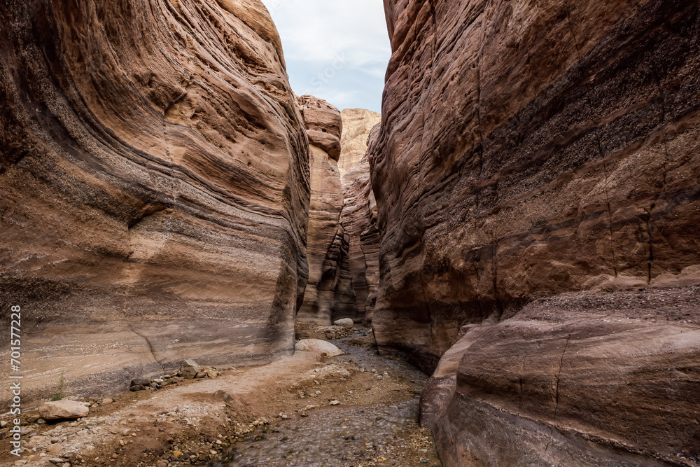 A shallow  stream flows between rocks painted with beautiful natural patterns at beginning of the Wadi Numeira hiking trail in Jordan