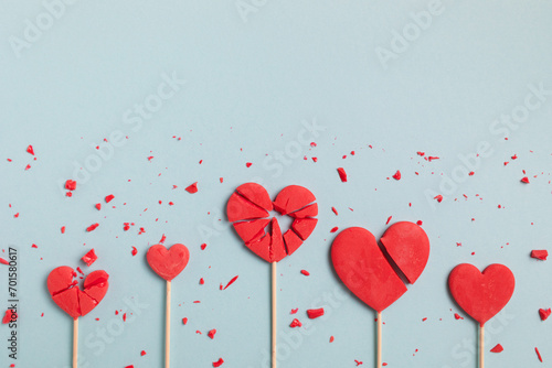 Valentine day concept with broken red lollipop hearts on pastel blue background top view. Flat lay greeting card..