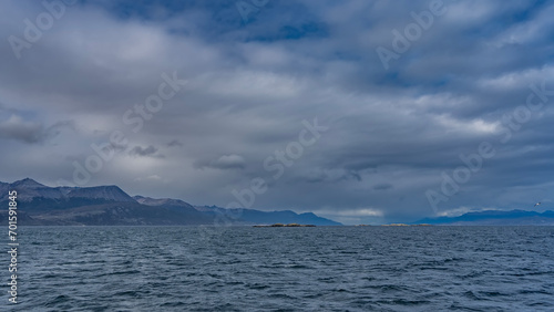 A calm seascape. Ripples on the surface of the blue ocean. Clouds in the azure sky. The Andes mountain range in the distance. Argentina. Beagle Channel. Tierra del Fuego Archipelago © Вера 