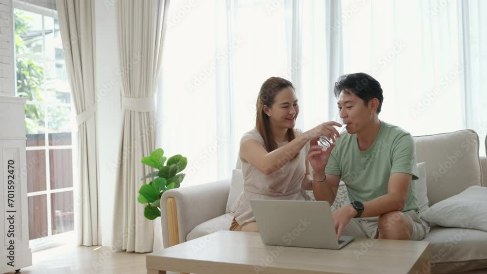 Asian couple sitting at home working with laptop
Asian couple sitting at home working with laptop