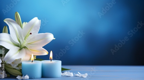 lily flowers and burning blue candles on blue background with space for text