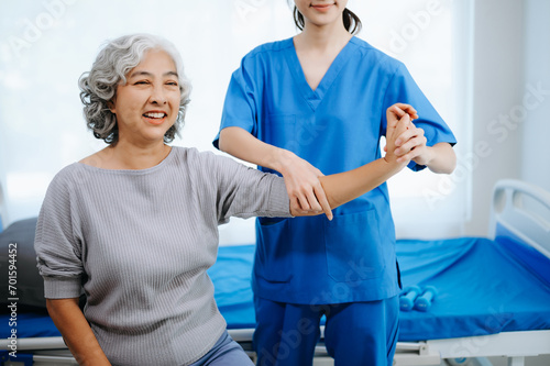 Asian physiotherapist helping female patient stretching arm during exercise correct with dumbbell in hand during training hand