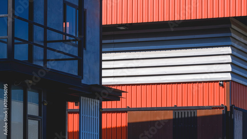 Geometric lines pattern background in street minimal style. Aluminium louver of orange metal warehouse near modern office industrial building with sunlight and shadow on surface, perspective side view photo