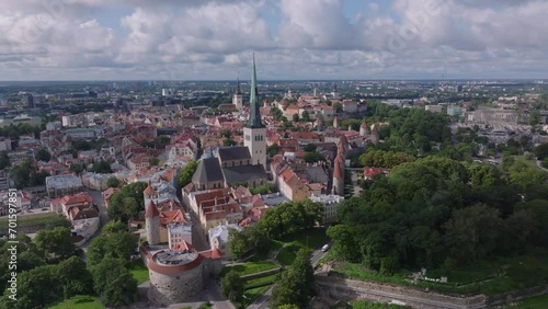 Aerial slide and pan footage of Oleviste kogudus church with tall tower. Historic city center with tourist landmarks. Tallinn, Estonia photo