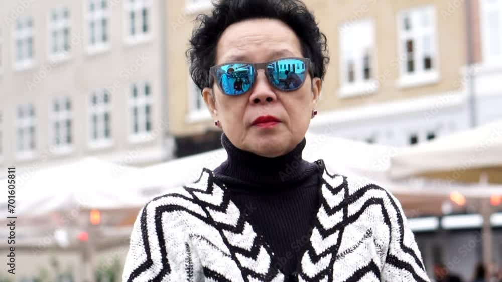 asian senior woman wearing sunglasses walking in Europe downtown asian senior woman wearing sunglasses walking in Europe downtown