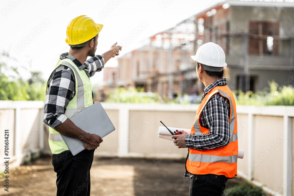Obraz premium Asian people, two man, holding blueprints Structural engineers examine structural plans for office buildings and housing developments on-site, discussing work at construction site.