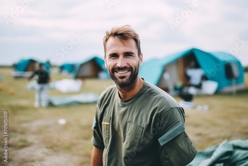 Portrait of happy man standing near tent at campsite in countryside