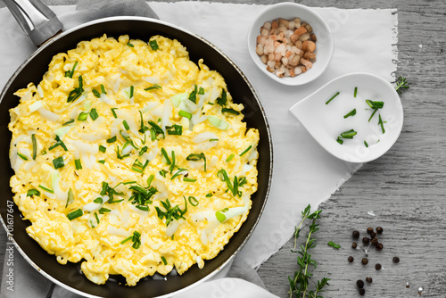 delicious scrambled eggs. scrambled eggs in a frying pan with chopped green onions and dill, white gravy boat. breakfast concept