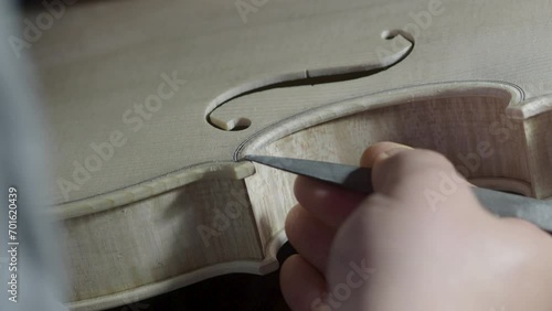 macro close up of artisan luthier maker work on new classic handmade raw violin smooth edge in waist and purfling rasp in workbench of workshop in Cremona Italy 4k video photo