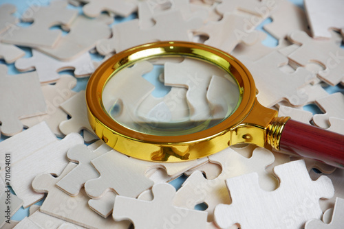 magnifying glass and on the missing puzzle piece. photo illustration concept of searching for and recruiting new employees