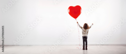 Back view of a kid raising arms with red love valentine heart shaped balloon isolated on white background