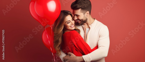 Cheerful couple in love hugging on a romantic Valentine with red heart shaped balloon isolated red background