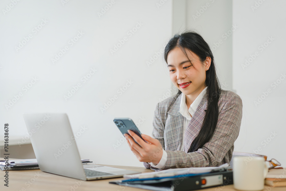 Asian businesswoman happy and cheerful while using smartphones and working. Young businesswoman using apps on cell phones, reading news. Asian businesswoman happy and cheerful while using smartphones and working. Young businesswoman using apps on cell phones, reading news.