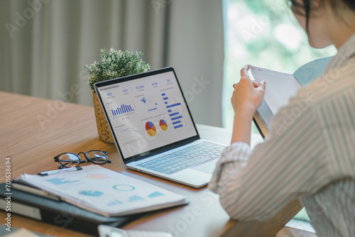 Businesswoman accountant using a graphs and charts to analyze market data, balance sheets,accounts,and net profits in order to plan new sales strategies and increase production capacity. photo