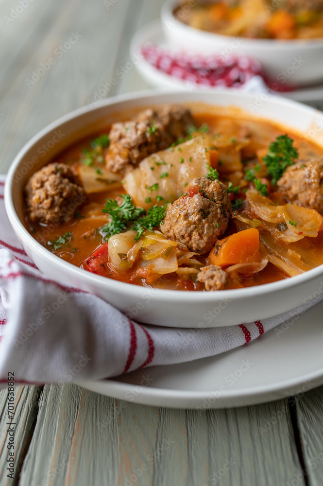 Soup with meatballs cabbage and vegetables on a plate.