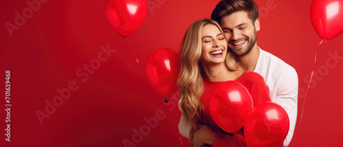 Cheerful couple in love hugging on a romantic Valentine with red heart shaped balloon isolated red background
