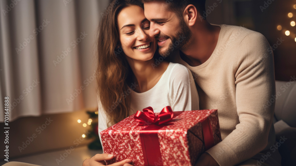 Lovely young couple hugging at home holding gift box, happy giving concept. Lovely young couple hugging at home holding gift box, happy giving concept.