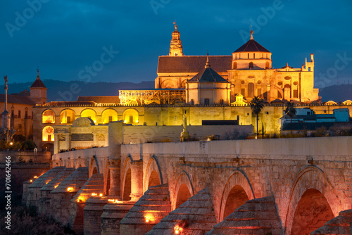 View of the Roman bridge over the Guadalquivir river and the mosque and cathedral in Cordoba, Andalusia, Spain with artificial colorfu light at night photo