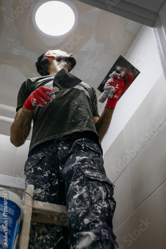 A man plastering the ceiling. Smoothing the walls and preparing for painting.