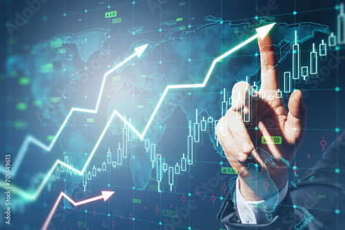 Close up of man hand pointing at growing upward chart, map, arrows and forex graph on blurry background. Global trends, trading and finance concept. Double exposure. photo
