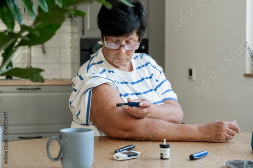 Senior woman injecting insulin with syringe at home photo