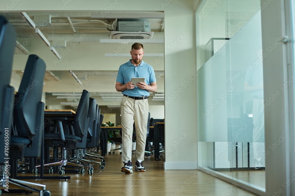 Businessman walking and using tablet PC in office Businessman walking and using tablet PC in office