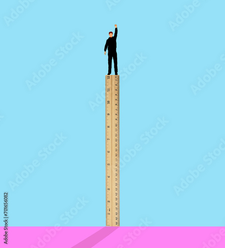 Man standing on ruler against colored background photo