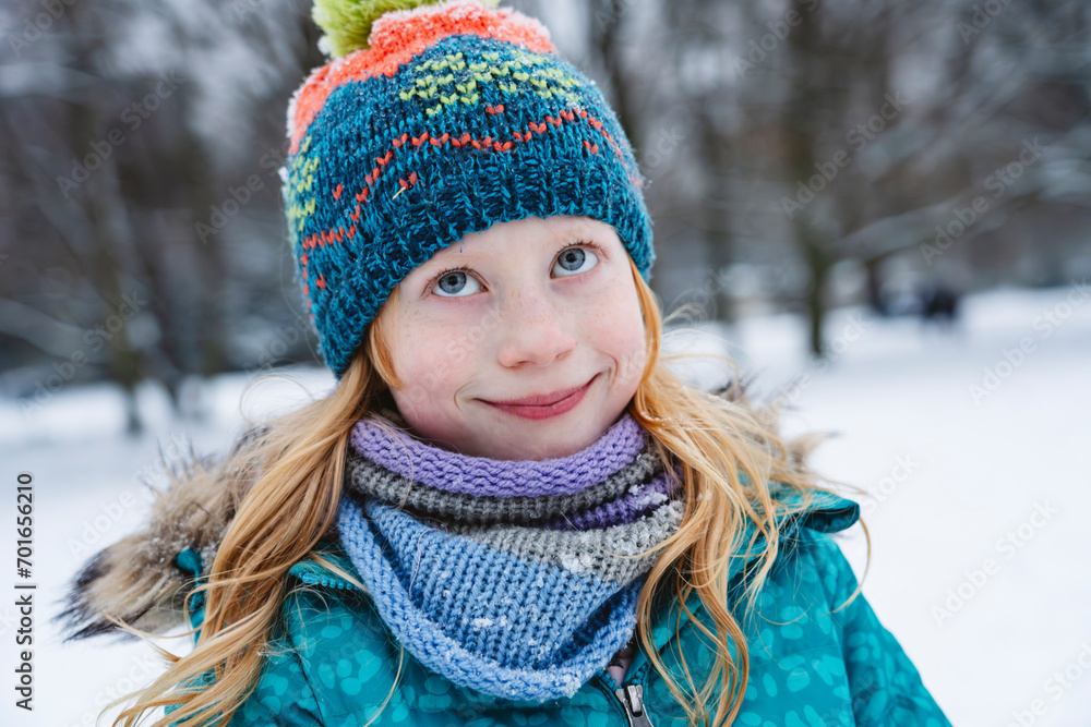 Smiling blond girl wearing scarf and knit hat in winter Smiling blond girl wearing scarf and knit hat in winter