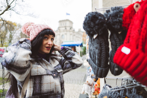 Woman wearing knit hat and buying from market in city photo