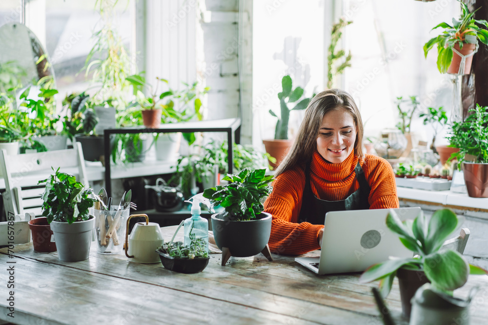 © Westend61 - Smiling botanist working on laptop at plant store