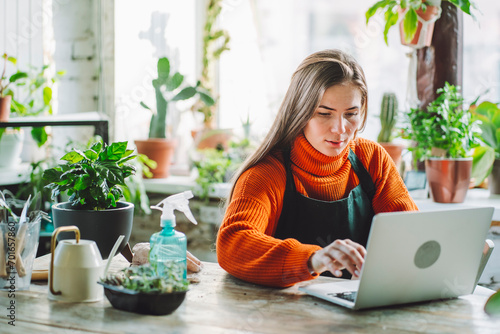Botanist working on laptop at table in plant store