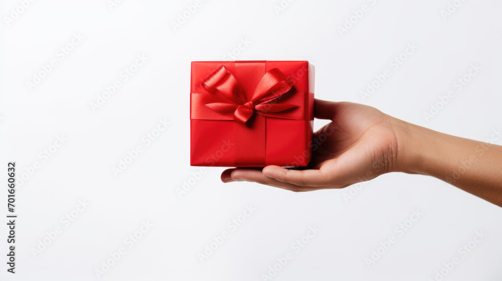 Hand holding a red gift box with ribbon on white background Hand holding a red gift box with ribbon on white background