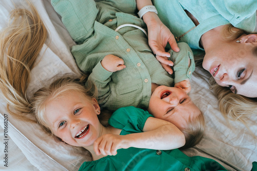 фотографія Overjoyed mother and children sharing laughter on a bed, a heartwarming family m