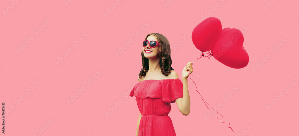 Portrait of happy smiling young woman holding pink heart shaped balloon on studio background Portrait of happy smiling young woman holding pink heart shaped balloon on studio background