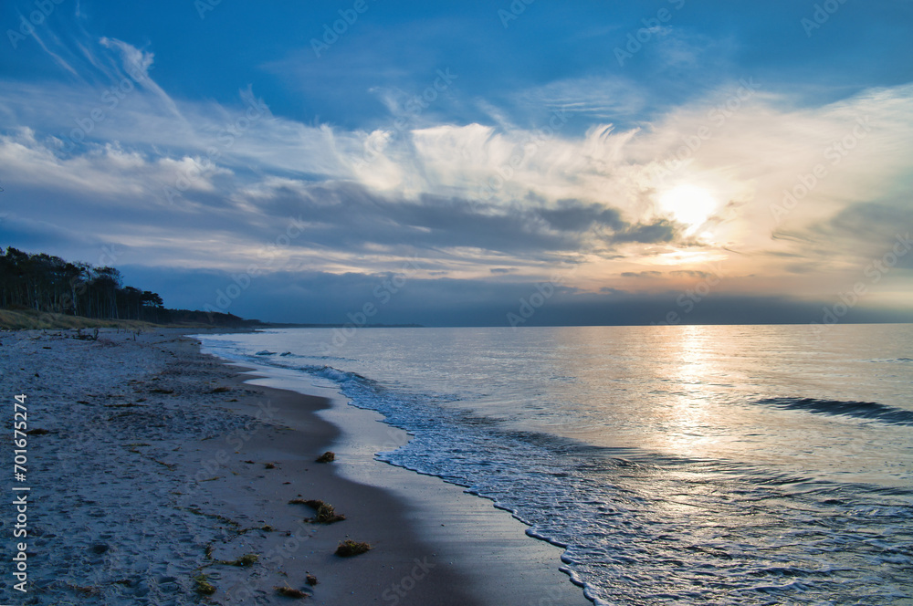 Sunset on the west beach on the Baltic Sea. Waves, beach, cloudy sky. Landscape