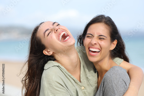 Two joyful friends laughing hilariously on the beach photo