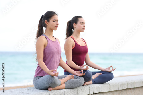 Two women doing yoga exercise on the beach