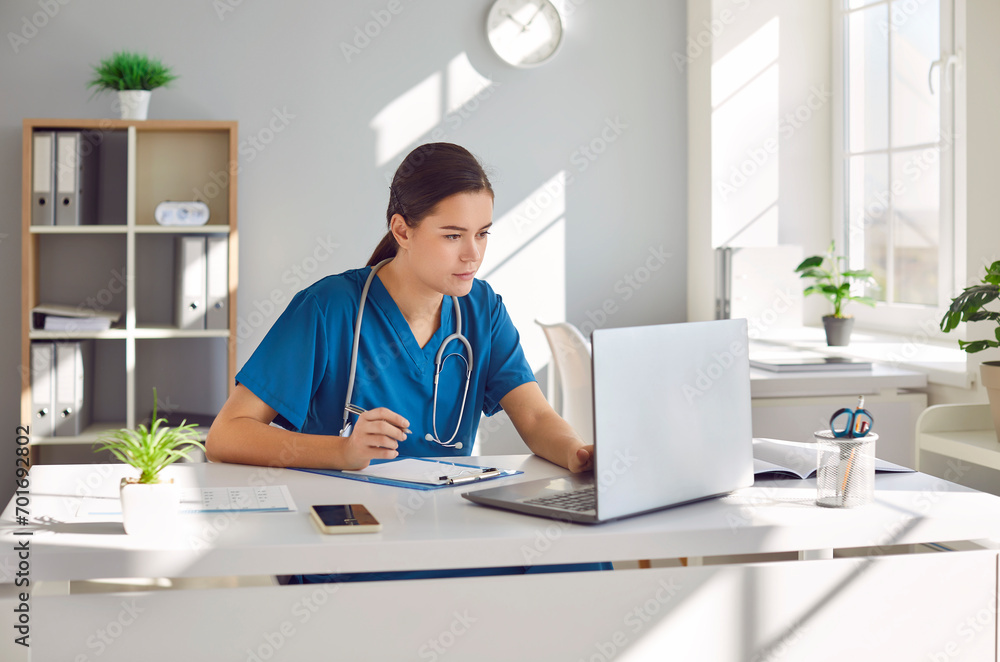 In the virtual realm of healthcare, Focused woman doctor or nurse using a laptop computer in hospital office. This poignant image captures the essence of online medical practices through internet. In the virtual realm of healthcare, Focused woman doctor or nurse using a laptop computer in hospital office. This poignant image captures the essence of online medical practices through internet.