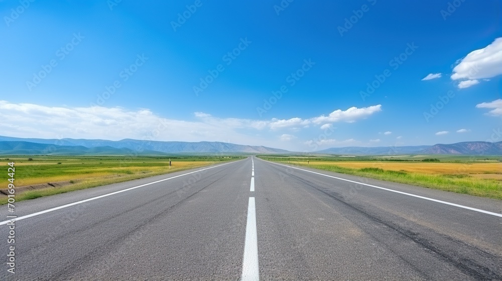 highway in the grassland background of blue sky and bright clouds, long road stretches into the distance. empty street on a beautiful sunny day