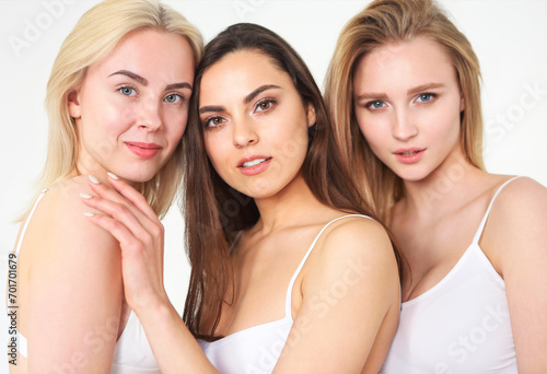 Group of happy different women in white hugging over white background.