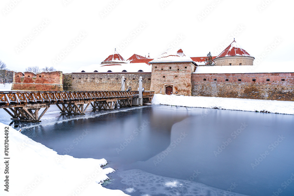 Fagaras fortress surrounding by a frozen lake during winter times in Fagaras, Brasov county, Transylvania, Romania