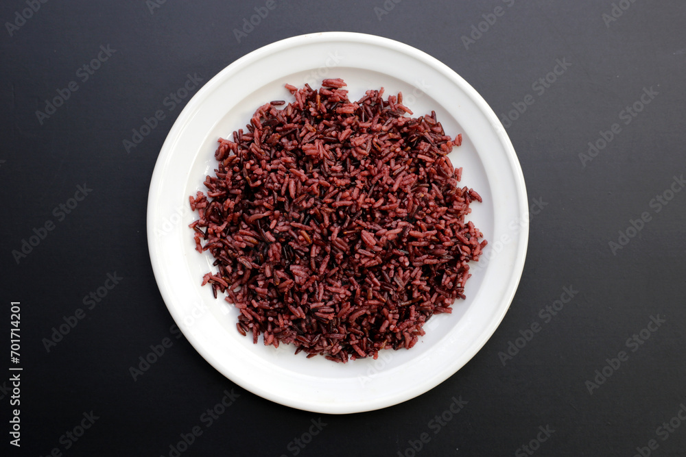 Cooked black berry rice in white plate on dark background. Cooked black berry rice in white plate on dark background.