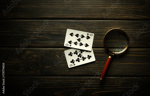 Gambling game of poker with one pair combination. Magnifying glass and cards on a black vintage table in a poker club
