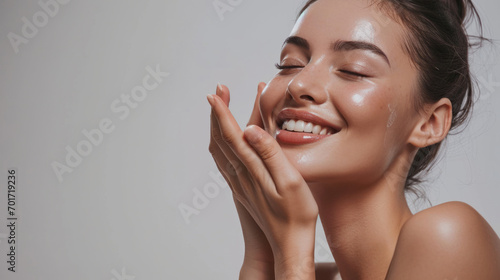 Skincare. Woman with beautiful face touching healthy facial skin. Woman smiling while touching her flawless glowy skin with copy space for your advertisement, skincare