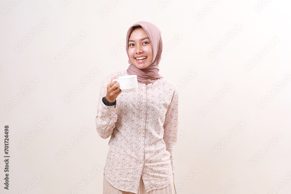 Happy young asian muslim woman standing while holding a cup of coffee. Isolated on white Happy young asian muslim woman standing while holding a cup of coffee. Isolated on white