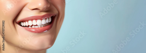 Close up shot of a woman's smile with white healthy teeth isolated on a light background. Banner for dentistry