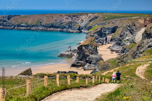 Bedruthan Steps, Cornwall, UK - The famous sea stacks, with pathway and couple in hats looking at view.