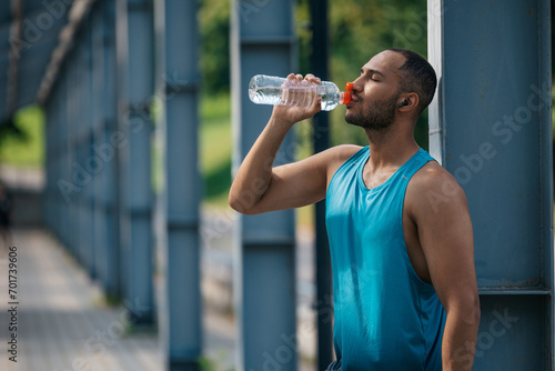 Well-built handsome sportsman drinking water after workout photo