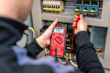 Worker measuring and repairing an electrical system panel